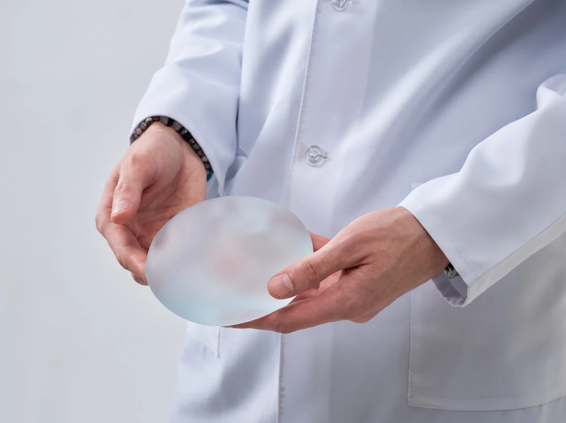 Cirurgião segurando uma prótese de silicone durante a explicação do procedimento