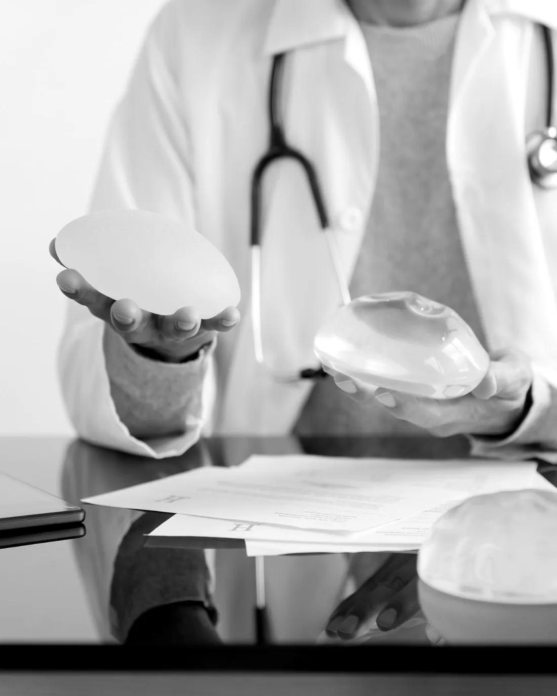 Médico segurando implantes mamários durante a consulta de avaliação