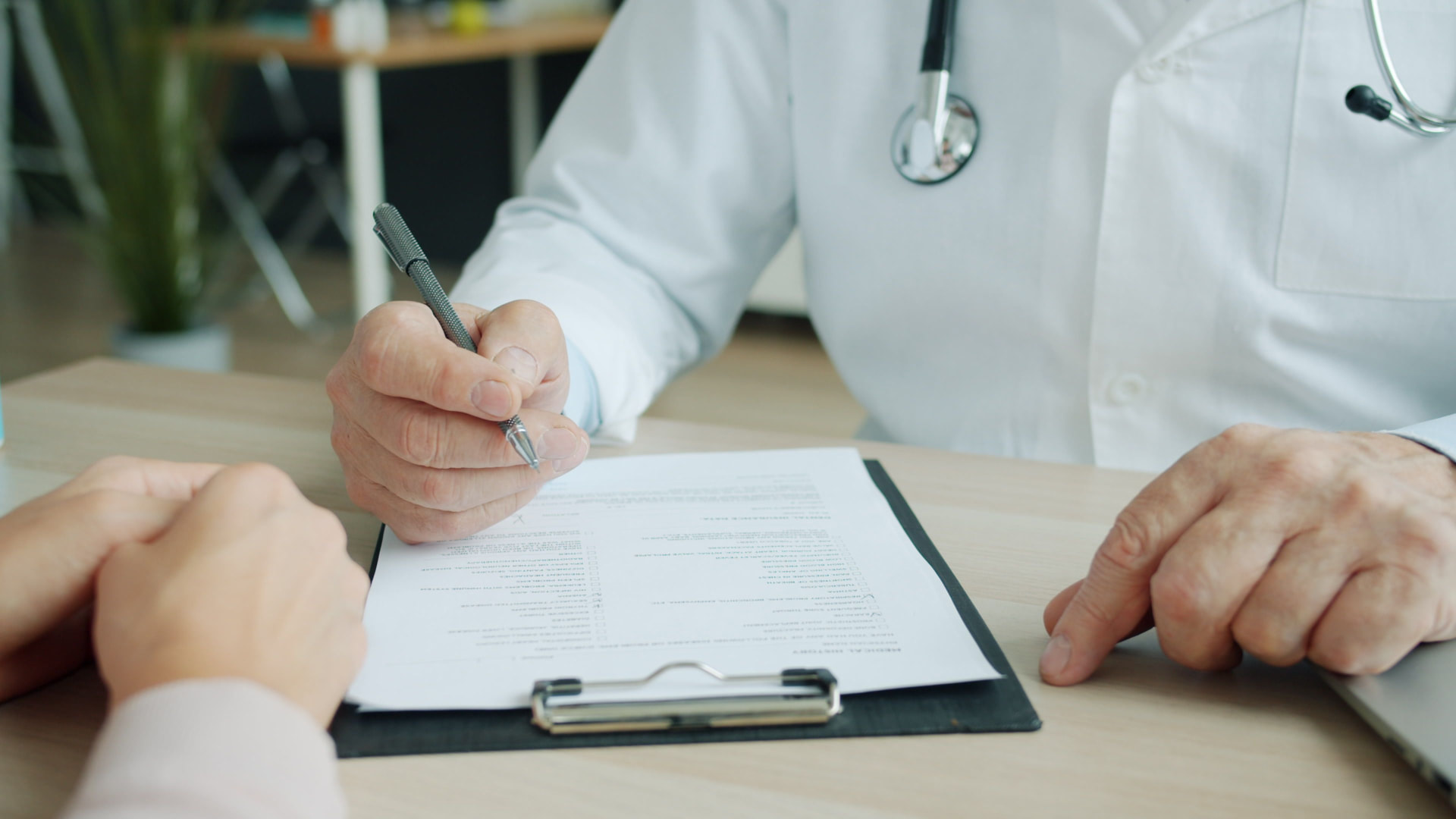 Médico preenchendo a ficha de avaliação durante a consulta de cirurgia plástica