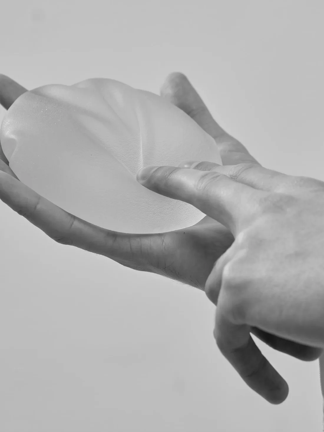 Mãos segurando um implante mamário de silicone