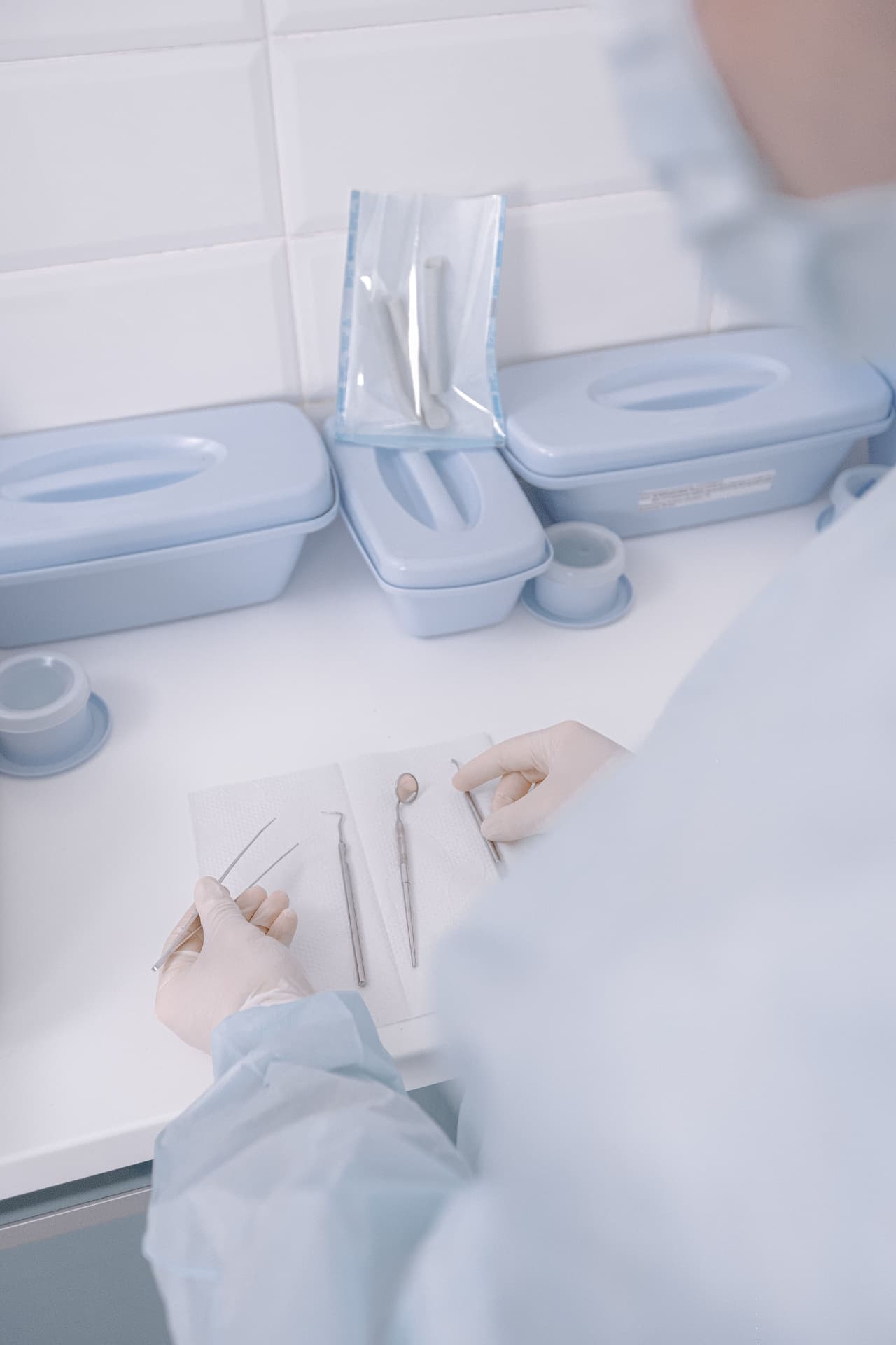 Profissional de saúde uniformizada e com luvas organiza instrumentais cirúrgicos esterilizados sobre uma bancada